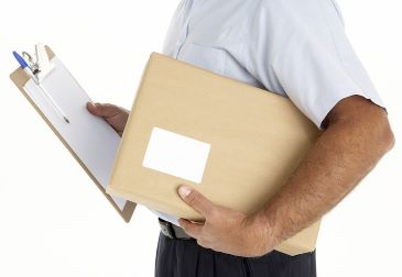 A delivery person is holding a clipboard and a labeled package.