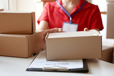 Courier hands giving packaged parcel at table.