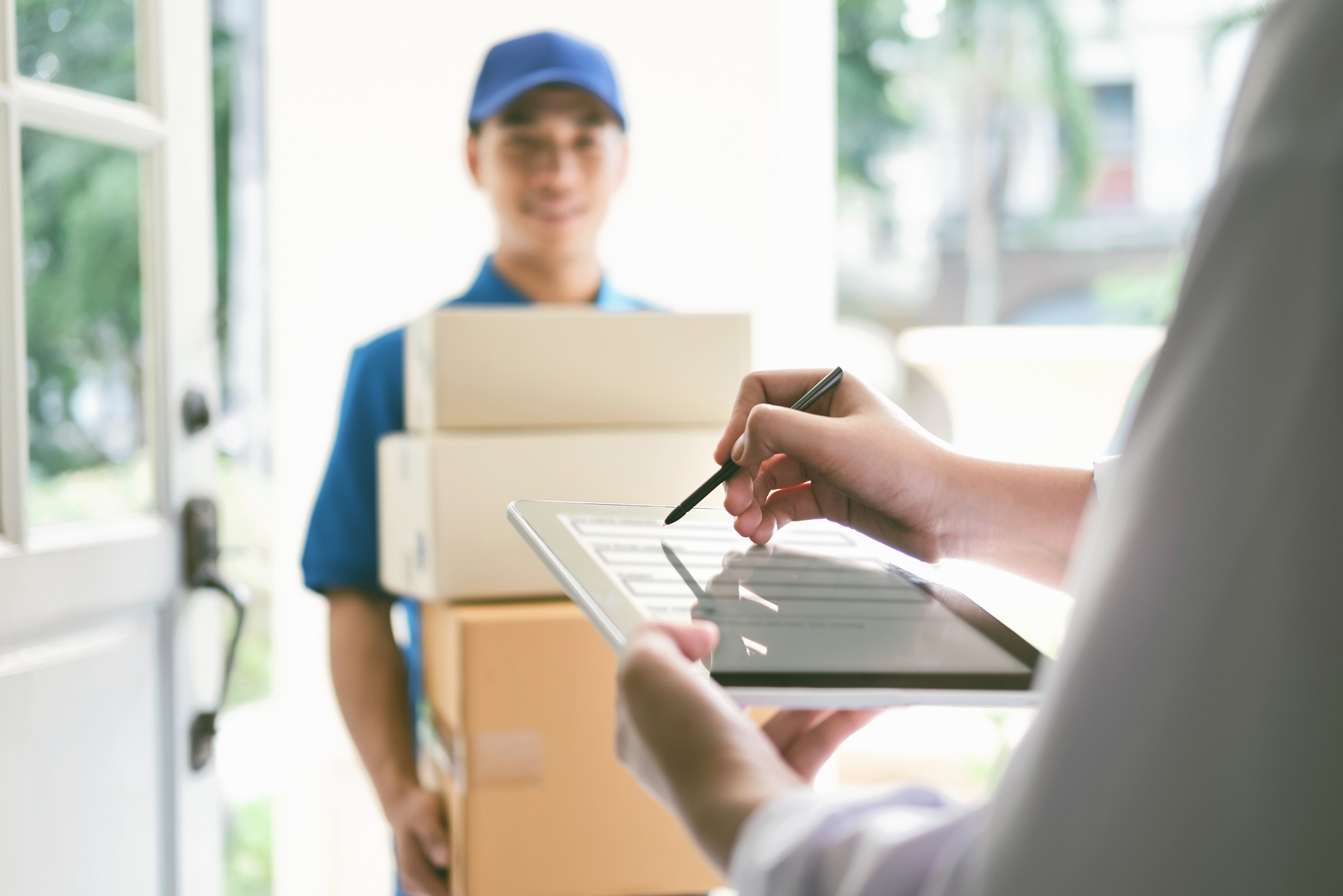 delivery mail people and shipping concept.Young woman sign in digital mobile phone after receiving parcel from courier at home.